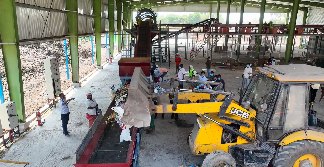 Bulk transfer hub with JCB loader feeding conveyor inside processing shed