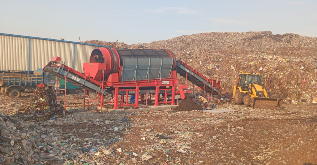Trommel screening unit and backhoe loader processing legacy waste at an HR Square concession site